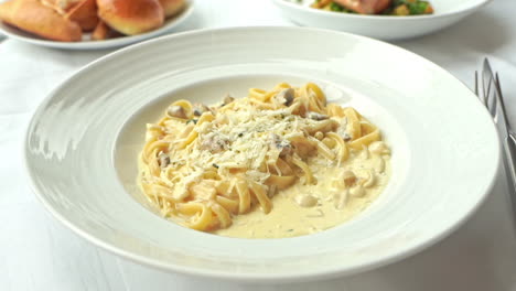 Parmesan-cheese-is-sprinkled-over-spaghetti-Pasta-with-mushrooms-and-cream-sauce-on-a-plate-in-Italian-Restaurant