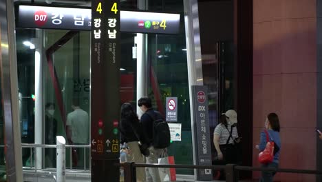 People-In-Masks-Walking-Through-The-Exit-Of-Gangnam-Station-In-Seoul,-South-Korea