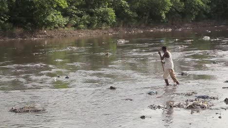 Ein-Junge-Geht-über-Einen-Fluss-In-Pakistan,-Der-Mit-Giftigem-Müll-Im-Wasser-Entsorgt-Wird