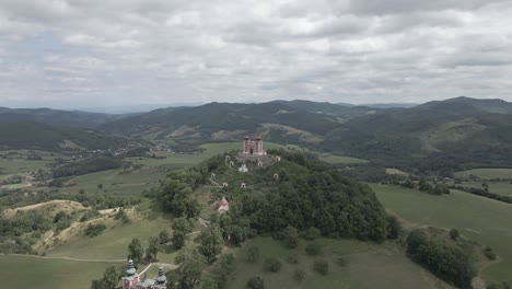 Pequeña-Capilla-En-La-Cima-De-La-Colina-Rodeada-De-Montañas-En-Eslovaquia-Durante-El-Día-Nublado
