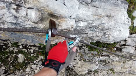 POV-of-via-ferrata-climber-securing-himself-by-placing-the-snap-links-one-after-another-into-the-next-segment