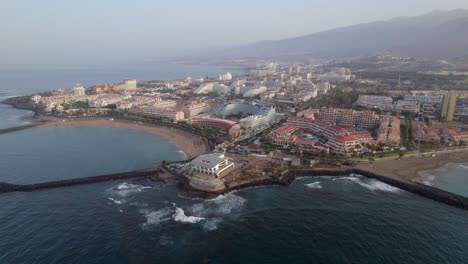 Aerial-view-of-waves-rolling-into-Playa-de-las-Americas-at-Tenerife-island,-Canary-islands,-Spain