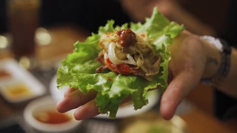 Hand-Mit-Ssam---Koreanischer-Schweinebauch-Eingewickelt-In-Salatblätter-Mit-Ssamjang-Und-Zwiebeln