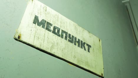 Medical-office-sign-inside-the-abandoned-Soviet-underground-bomb-shelter,-old-Soviet-Cold-war-bunker,-apocalypse,-handheld-medium-close-up-shot