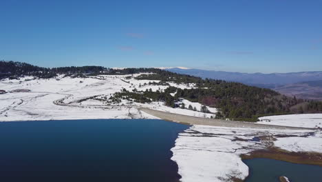 Vista-Aérea-De-La-Cordillera-Cubierta-De-Nieve-Y-El-Lago-En-Invierno
