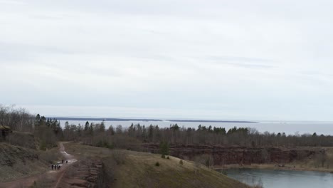 Pan-down-Aerial-view-drone-flight-over-lake-in-Kinnekulle-Sweden-view-to-Vänern-lake