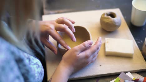 Young-woman's-hands-crafting-a-bowl-with-clay-on-a-pottery-workshop
