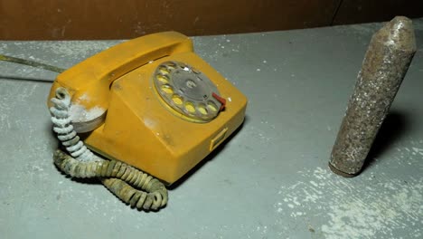 Old-yellow-telephone-inside-the-abandoned-Soviet-underground-bomb-shelter,-old-Soviet-Cold-war-bunker,-apocalypse,-medium-handheld-shot