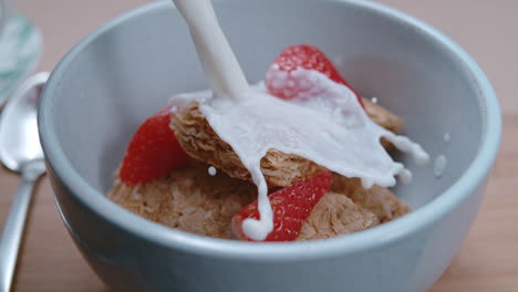 Dynamic-milk-pour-on-bowl-of-breakfast-cereal-and-strawberries