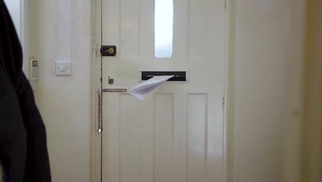 Mail-letter-being-delivered-through-a-door-mounted-letterbox,-mailbox-opening