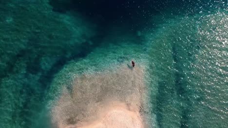 Weibliche-Touristin-Auf-Einer-Atemberaubenden-Insel-In-Italien,-Die-In-Das-Flache-Blaue-Meer-Mit-Kristallklarem-Wasser-Eintaucht---Luftaufnahme-Von-Oben