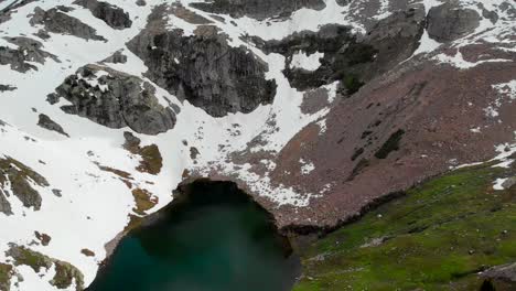 Rückwärts-Dolly-Luftaufnahme-Des-Sees-Zwischen-Hohen-Schneebedeckten-Bergen