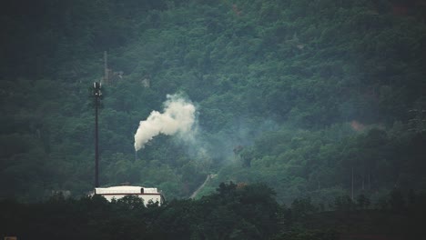 A-factory-near-a-mountain-range_produce-a-white-smoke_wide-shot_long-shot_50fps
