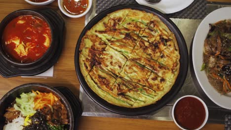 Variety-Of-Korean-Cuisine-Big-Plate-Of-Japchae,-Buchimgae,-Dakgaejang,-Bibimbap,-And-Samgyeopsal-In-Korean-Restaurant