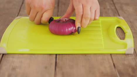 Women-cutting-red-onion-in-half-on-chopping-board