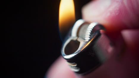 Super-slow-motion-macro-shot-of-a-lighter-being-lit-in-the-dark,-with-a-flame-coming-out