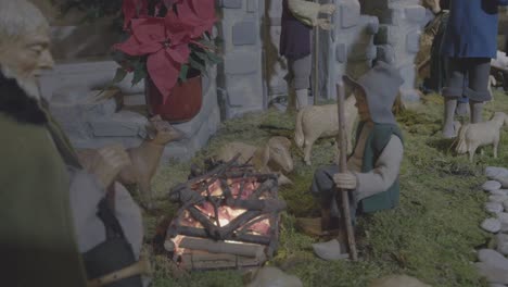 Two-shepherds-warming-themselves-by-the-fire-together-with-their-sheep-in-a-nativity-scene