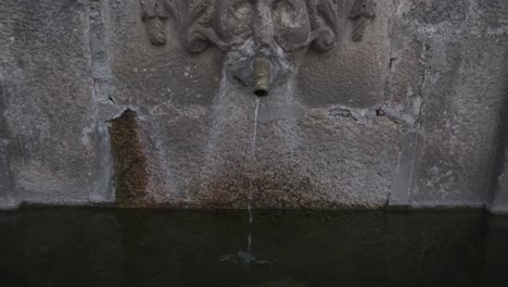 Water-flowing-from-wall-fountain-in-stone,-Monsanto-village-in-Portugal