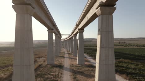 Slow-flight-between-the-tall-pillars-of-a-train-bridge-at-sunset-in-Israel