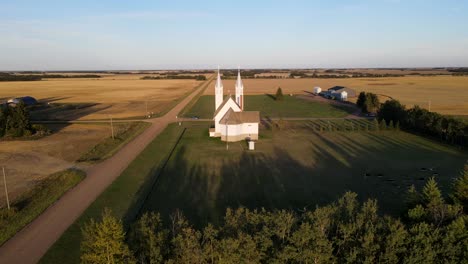 Aerial-flying-forward-shot-of-roman-catholic-church-in-north-American-prairie-during-sunset