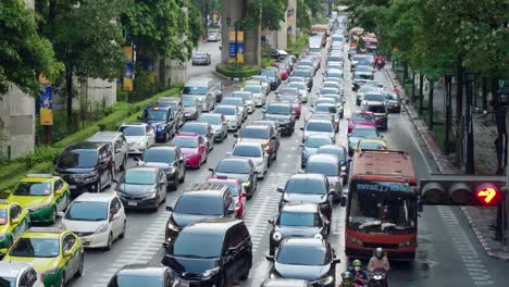 Wide-view-over-traffic-through-busy-intersections-at-rush-hour-in-Bangkok-which-is-controlled-by-traffic-lights,-there-is-heavy-traffic-every-day