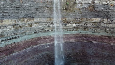 Spectacular-scenic-view-of-famous-Devil’s-Punchbowl,-rock-formation-with-waterfall-pouring-down-to-the-bottom-located-at-Hamilton,-Ontario-Canada,-slow-aerial-pedestal-down-shot