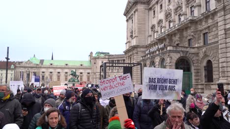 Personas-Sosteniendo-Carteles-Con-Diferentes-Mensajes-Durante-Las-Protestas-Contra-La-Corona-En-Viena,-Austria