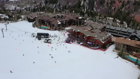 Winter-skiing-resort-complex-with-people-sliding-during-snowfall,-aerial-drone-view