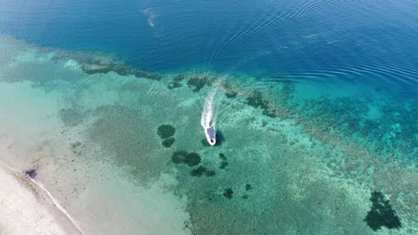 Dive-boat-moving-over-beautiful-turquoise-crystal-clear-ocean-with-stunning-coral-reef-in-Timor-Leste,-Southeast-Asia