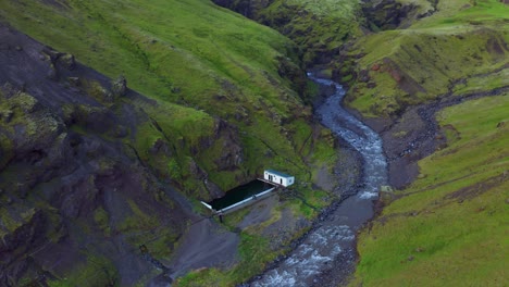 Famous-Outdoor-Swimming-Pool-Of-Seljavallalaug-With-Stream-On-Foothill-Of-Mountain-In-Iceland