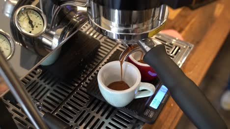 Espresso-machine-serving-two-cups-after-brewing-a-fresh-batch-of-grinded-coffee-on-a-weight-scale,-Close-top-angle-view