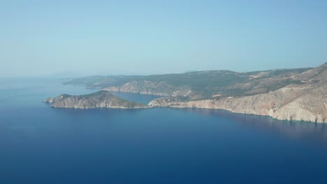 Aerial-wide-view-Assos-village-in-the-distance,-stunning-island-landscape,-Kefalonia-Island