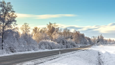 Time-lapse-shot-of-flying-clouds-at-blue-sky-during-snowy-winter-day---Melting-ice-frost-on-rural-road-beside-snowy-fields