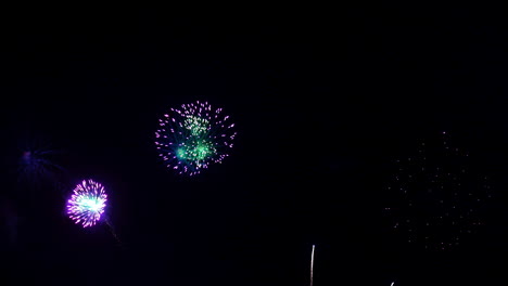 Purple-and-pink-fireworks-with-green-centers-explode-in-showers-of-light