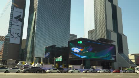 Car-traffic-near-World-Trade-Center-Seoul---STtown-Coex-Artium-with-Largest-curved-LED-Digital-outdoor-Billboard-Screen,-Trade-Tower-And-Parnas-Skyscrapers-at-sunset,-South-Korea