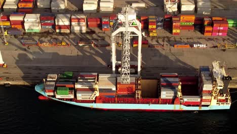 Aerial-view-of-a-container-commercial-boat-stacked-at-a-port-to-recieve-or-send-cargo-to-or-from-oversees