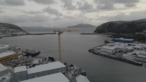 Scenic-View-Of-Town-With-Houses,-Buildings,-And-Wharf-Crane-Covered-In-Fresh-Snow-During-Winter-At-Skjervøy,-Northern-Norway