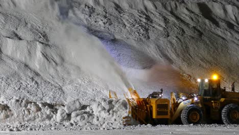 Slow-motion-Heavy-Bulldozer-blowing-snow-from-road-to-huge-Snow-pile,-Snowblower-working-at-Night