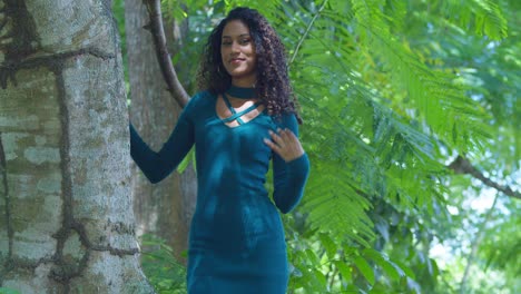 Slim-curly-hair-girl-stands-next-to-a-large-tree-trunk-on-a-tropical-island