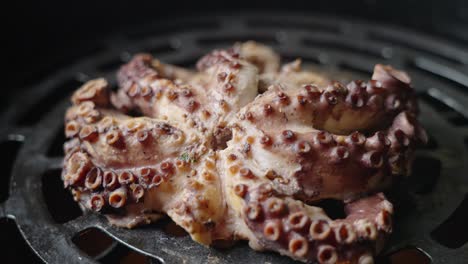 Cinematic-close-up-tracking-shot-of-an-octopus-being-cooked-over-an-open-flame-grill-barbeque,-capturing-the-details-texture-of-the-suction-cups-on-the-octopus-tentacles