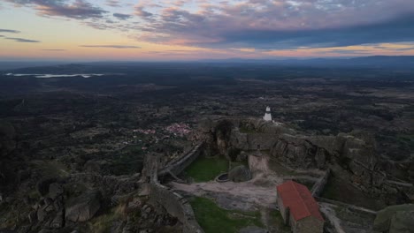 Drone-flying-over-Monsanto-Castle-at-sunrise,-Portugal
