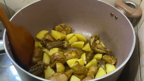 Brutzelnde-Hähnchen-Curry-Stücke-Mit-Gewürfelten-Kartoffeln-Im-Topf-Mit-Kochlöffel-Rühren