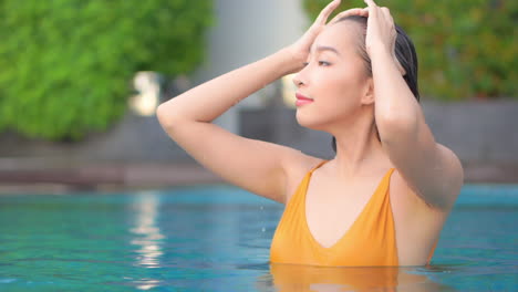 Beautiful-asian-woman-in-swimming-pool-touching-her-wet-hair-close-up-full-frame-slow-motion