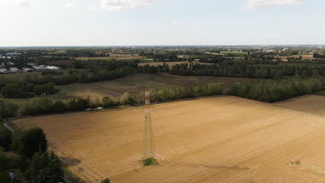 Electric-pole-of-high-voltage-air-cable-line-in-agriculture-fields,-aerial-drone-view