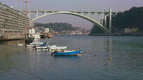 Einspielung-Von-Booten,-Die-Am-Fluss-Porto-Angedockt-Sind,-Mit-Brücke-Im-Hintergrund