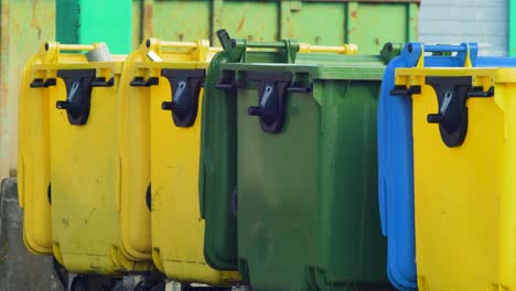 Colorful-plastic-garbage-bins-stacked-in-a-row-at-the-landfill,-environmental-pollution,-medium-shot