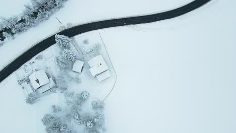 Aerial-shot-of-a-snow-covered-mountain-town,-winding-road-through-the-valley
