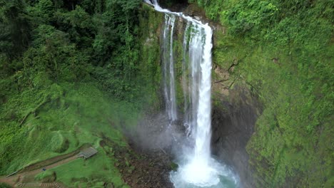 Aerial-lowering-on-Eco-Chontales-waterfall-falling-in-rocky-natural-pool-surrounded-by-green-tropical-forest,-Costa-Rica