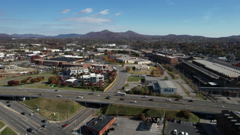 Aerial-view-of-traffic-on-Interstate-highway-passing-through-Roanoke-city,-Virginia-USA,-cars-and-neighborhood-buildings,-drone-shot