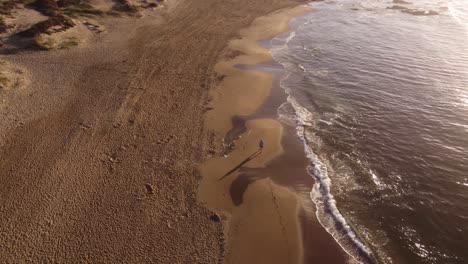Isolated-man-walking-on-beach-at-sunrise,-Punta-del-Este-in-Uruguay